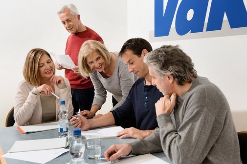 Besprechung im VdK-Büro Verschiedene Menschen sitzen an einem Tisch, offenbar in einer Arbeitssitzung, an der Wand hinter ihnen ist ein großes VdK-Logo.